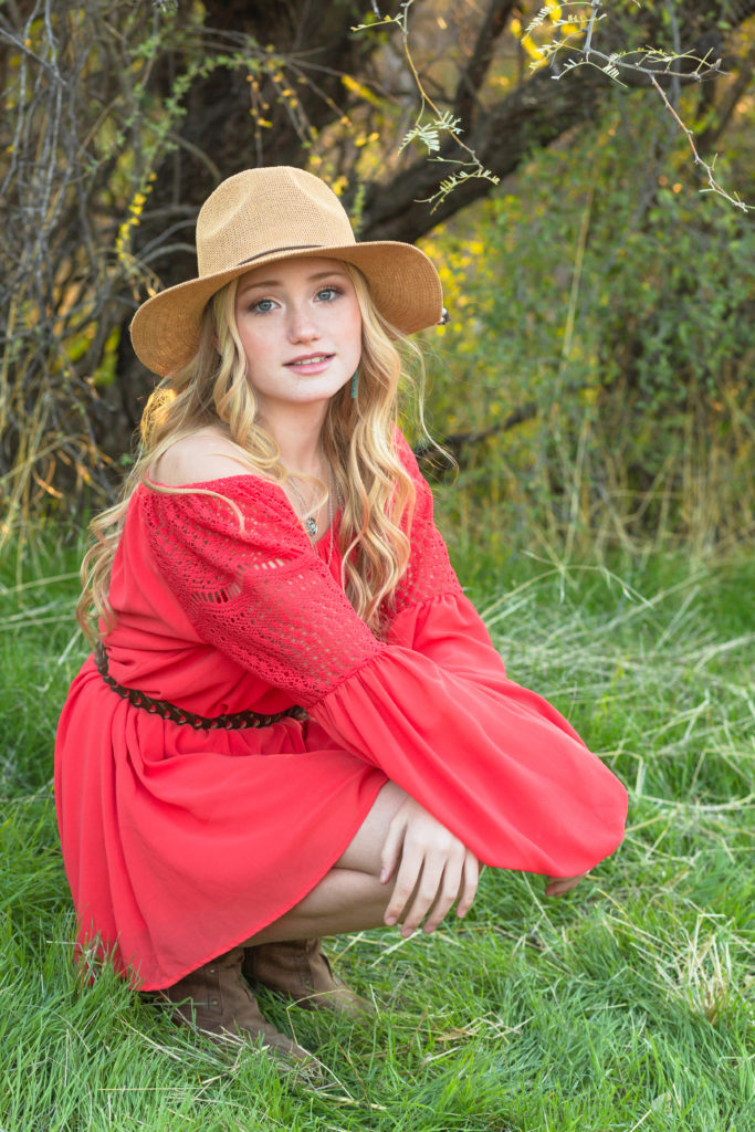 Model Addisyn smiles sweetly as she poses amidst the vibrant foliage during a styled senior portrait session.