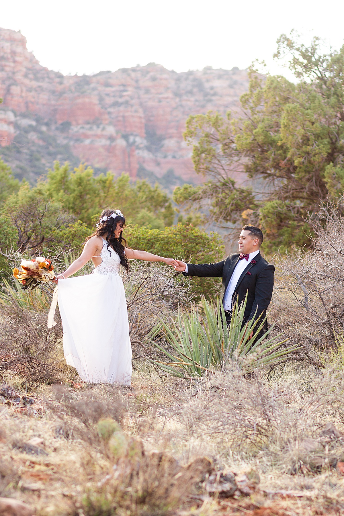 Husband leading wife down the trail surrounded by the stunning red rocks in Sedona.