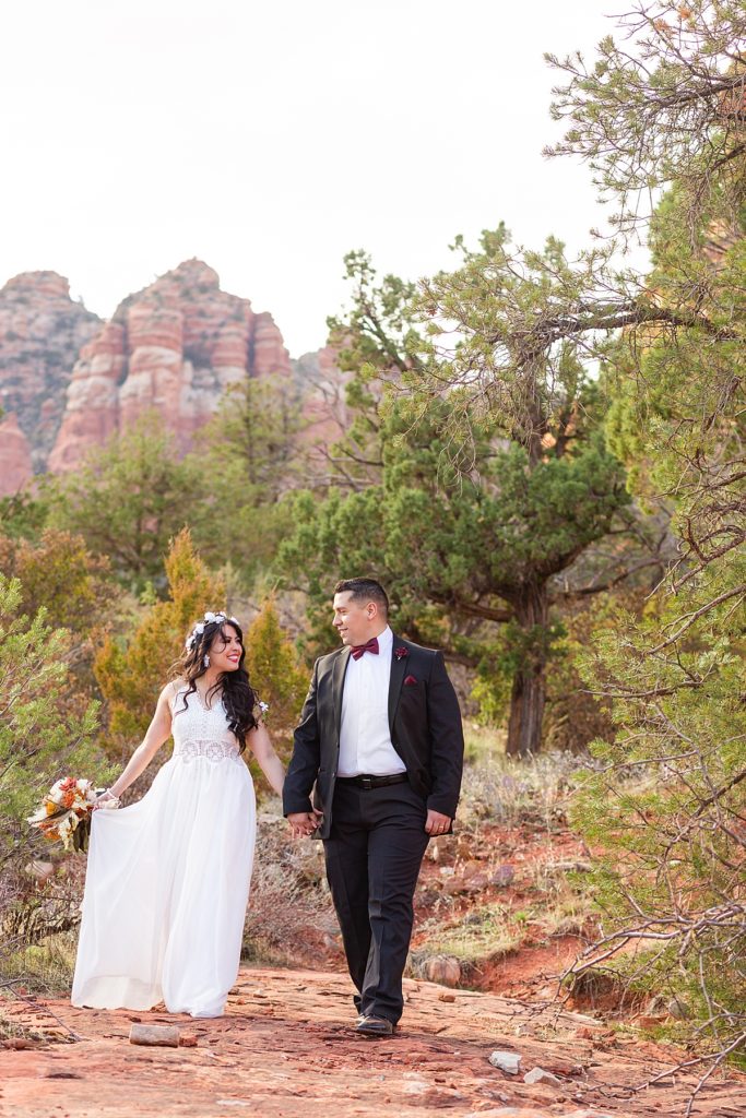 Couple smiles broadly at each other while walking the trail in Sedona during an anniversary photo session.