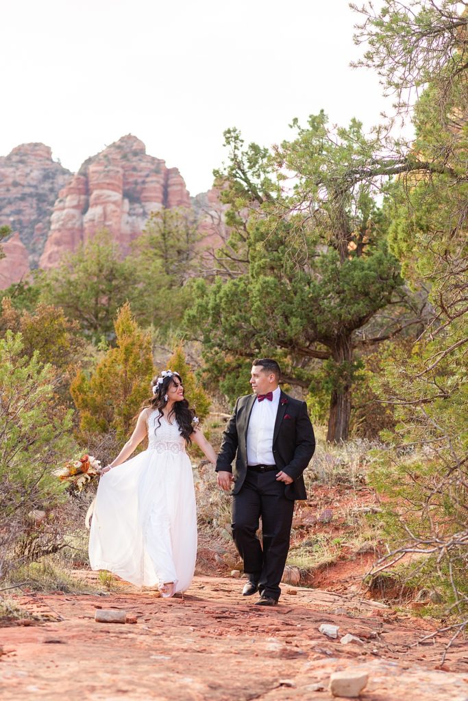 Joyful anniversary couple dances down the trail by beautiful Bell Rock in Sedona, Arizona.