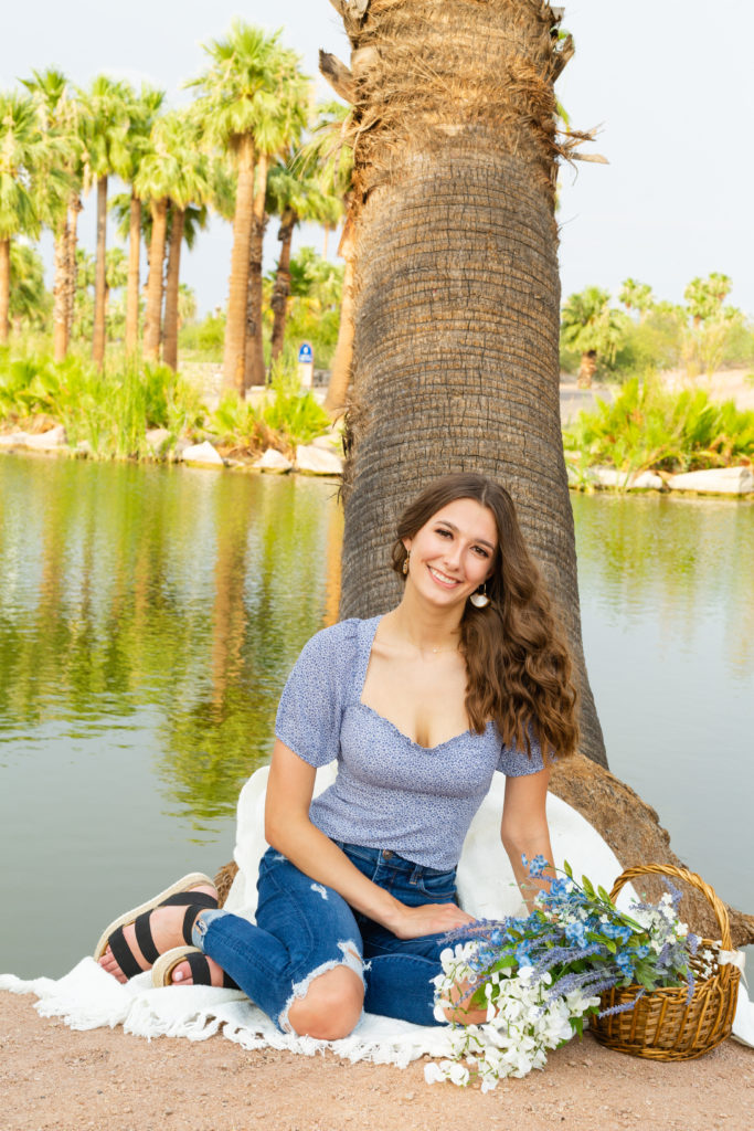 2022 senior grad Kylie grins as she poses in front of the water during her portrait session