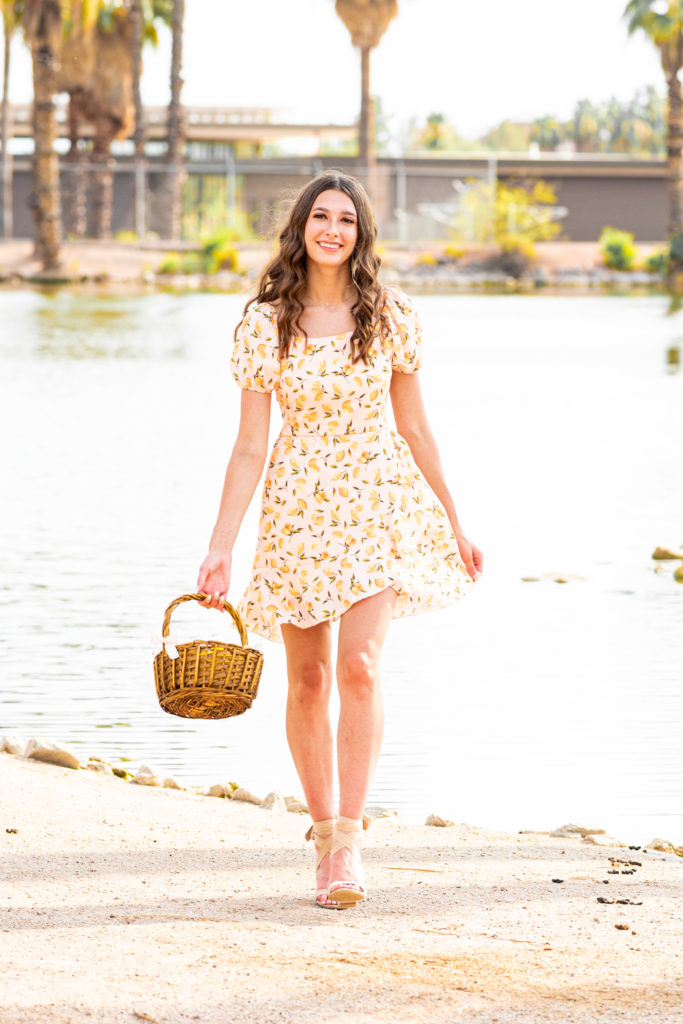 2022 senior grad Kylie model-walks toward the camera in a cute yellow dress during her senior portrait session