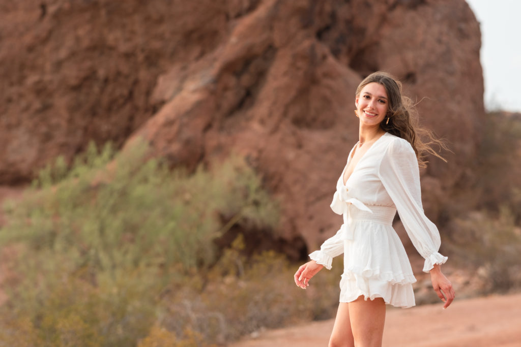 2022 senior grad Kylie twirls toward the camera wearing a short white dress during her portrait session