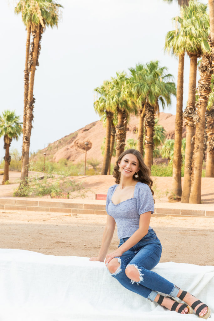 2022 senior grad Kylie smiles in a seated pose at Papago Park during her portrait session