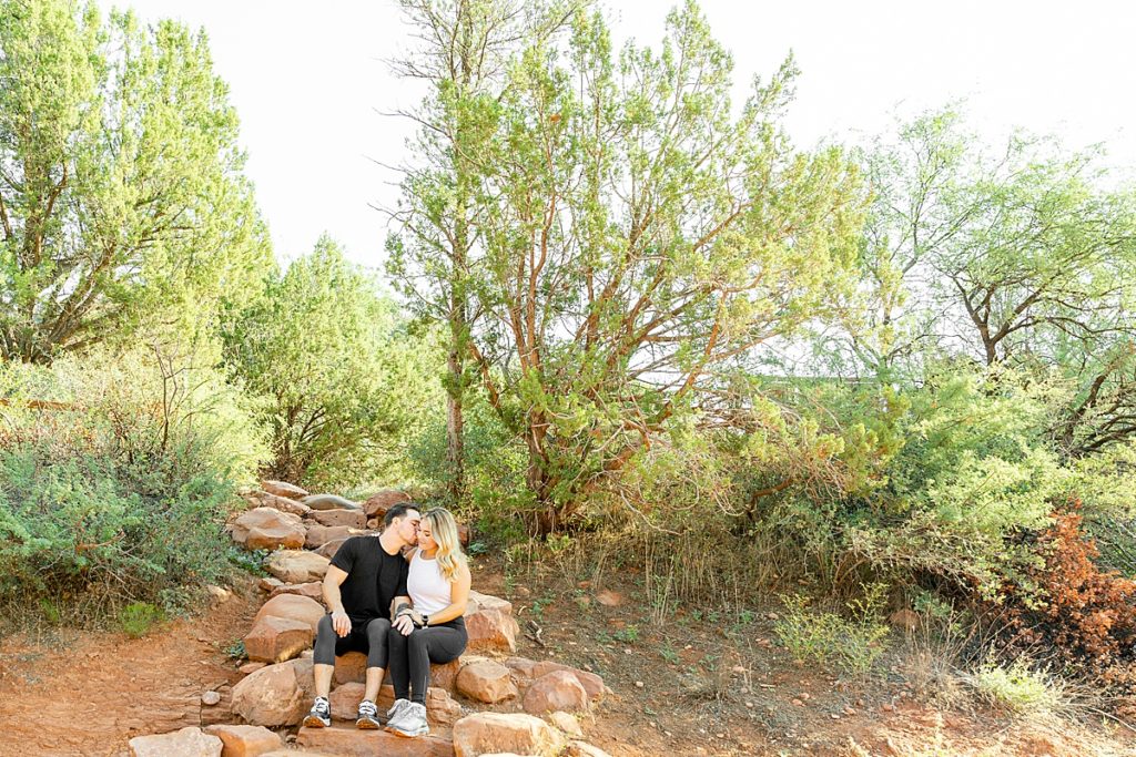 Dustin and Marissa sit in the sunlight during an engagement portrait session in Sedona