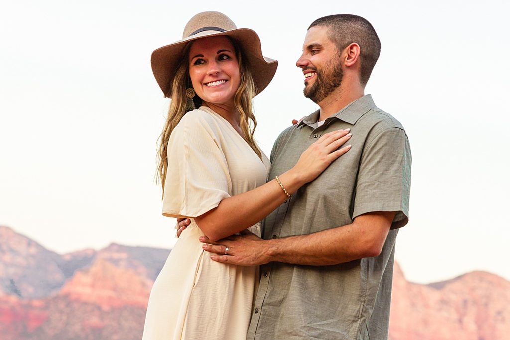 Bethany and Nick smile admiring the sunset during an anniversary portrait session in Sedona.