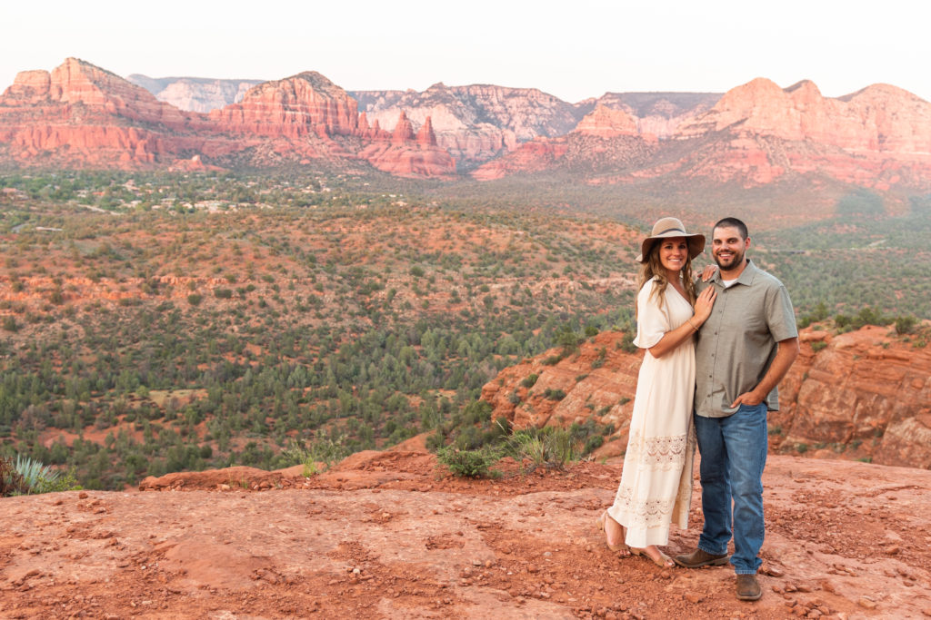 The stunning red rocks spanning behind them, Bethany and Nick smile during an anniversary photoshoot