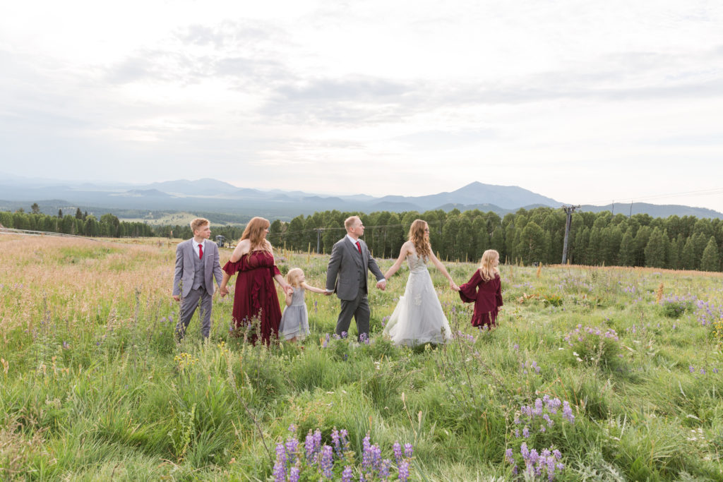 A fashionable family walks across the meadow in Flagstaff during a portrait session