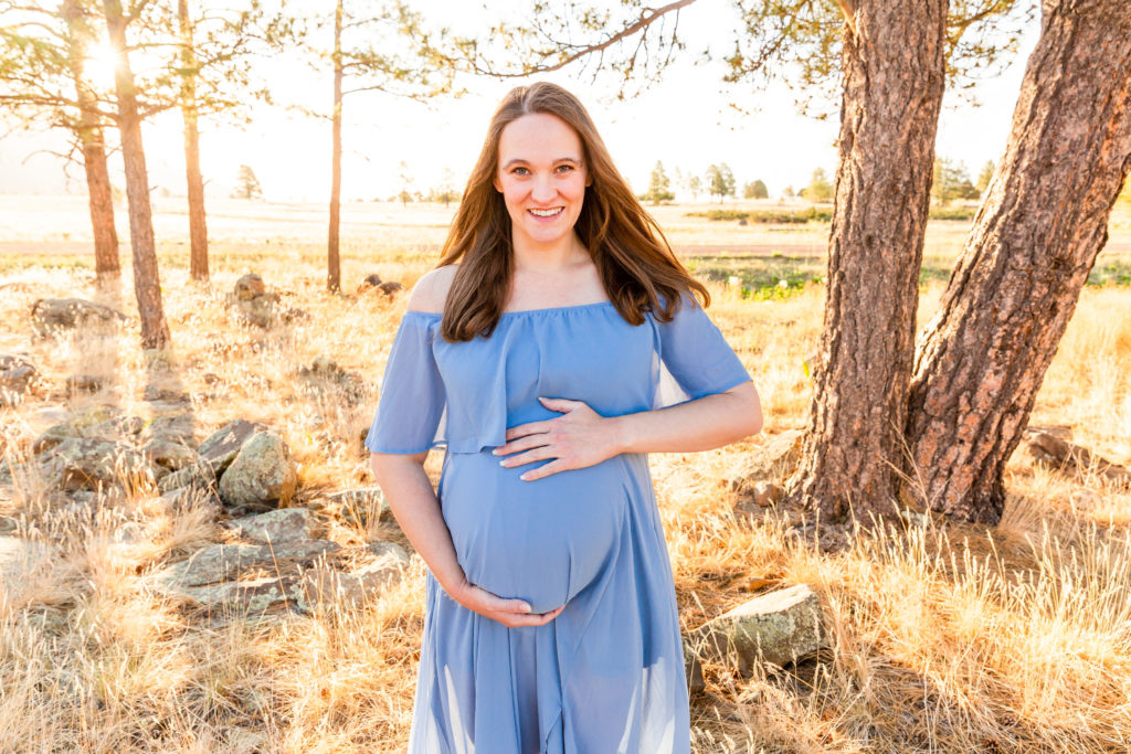 Expectant mother laughs joyfully in Flagstaff, Arizona during a maternity portrait session.
