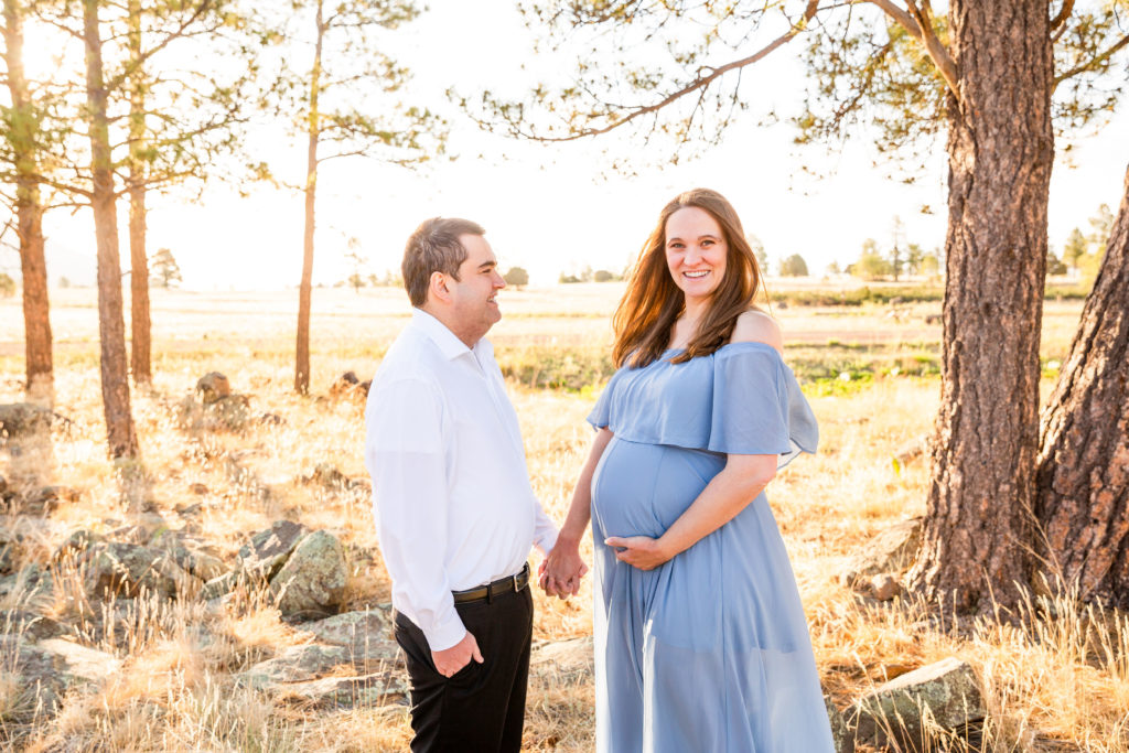 Husband admires expectant wife as she cradles her stomach during a maternity portrait session in Flagstaff, Arizona. 