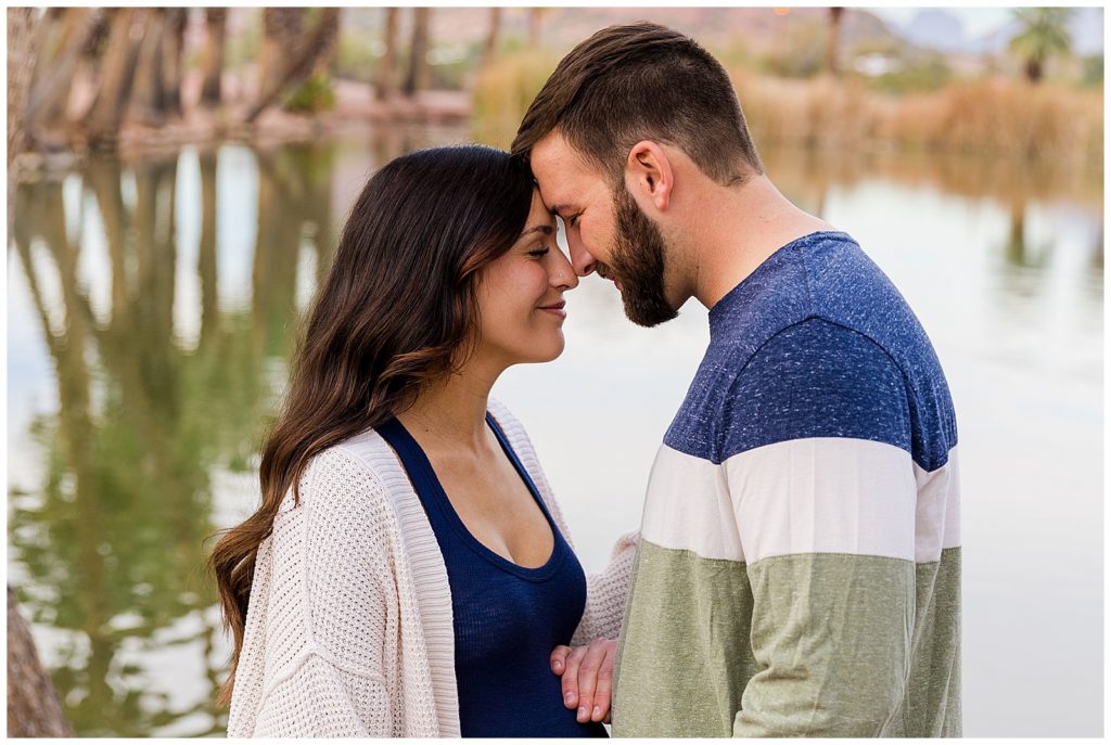 Smiling couple nuzzles close during maternity portraits session with Bayley Jordan Photography in Tempe, Arizona