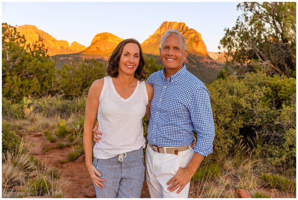 Mother and father smile at the camera as their kids joke behind the scenes during a family portrait session in Sedona, Arizona. 
