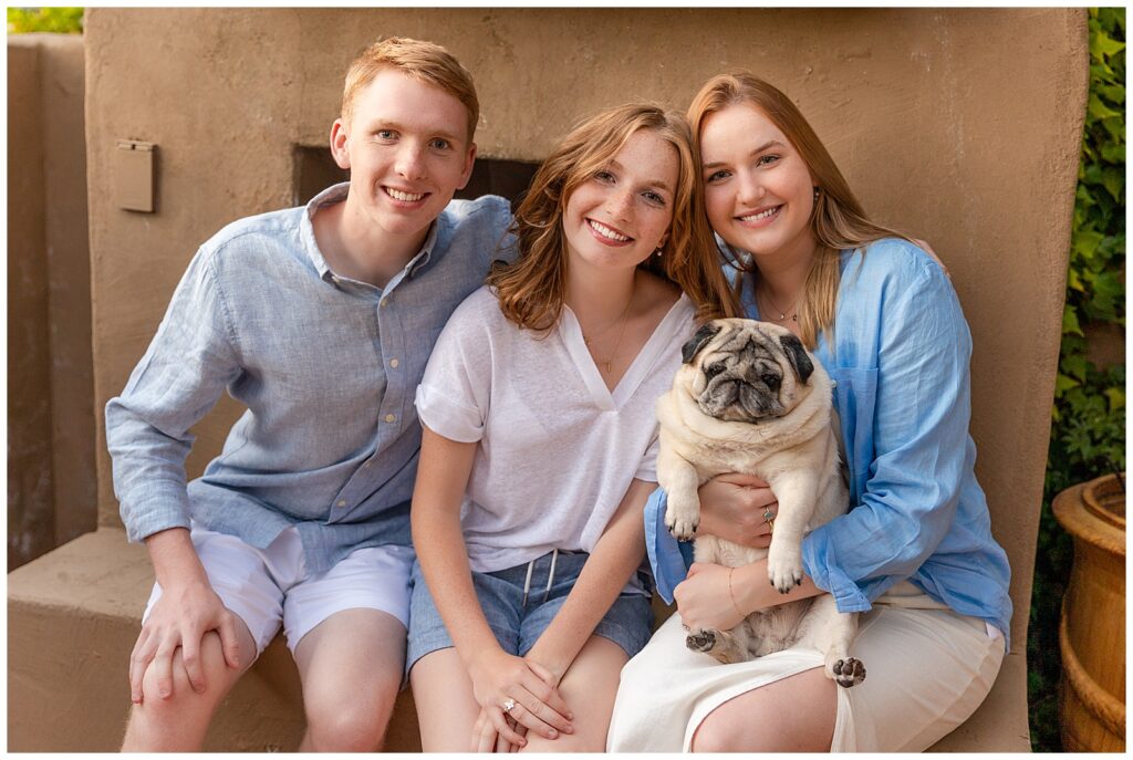 Siblings pose with adorable pet pug during sunset portrait session in Sedona, Arizona. 