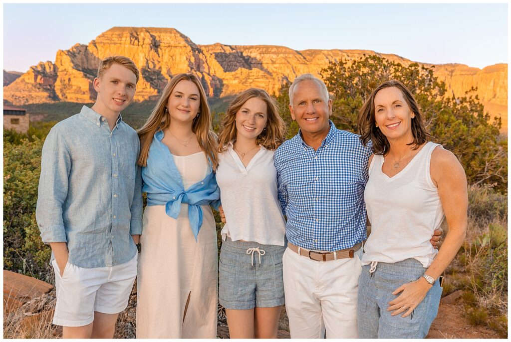 A family of five is all smiles during a portrait session with Bayley Jordan Photography in Sedona amidst the red rocks. 