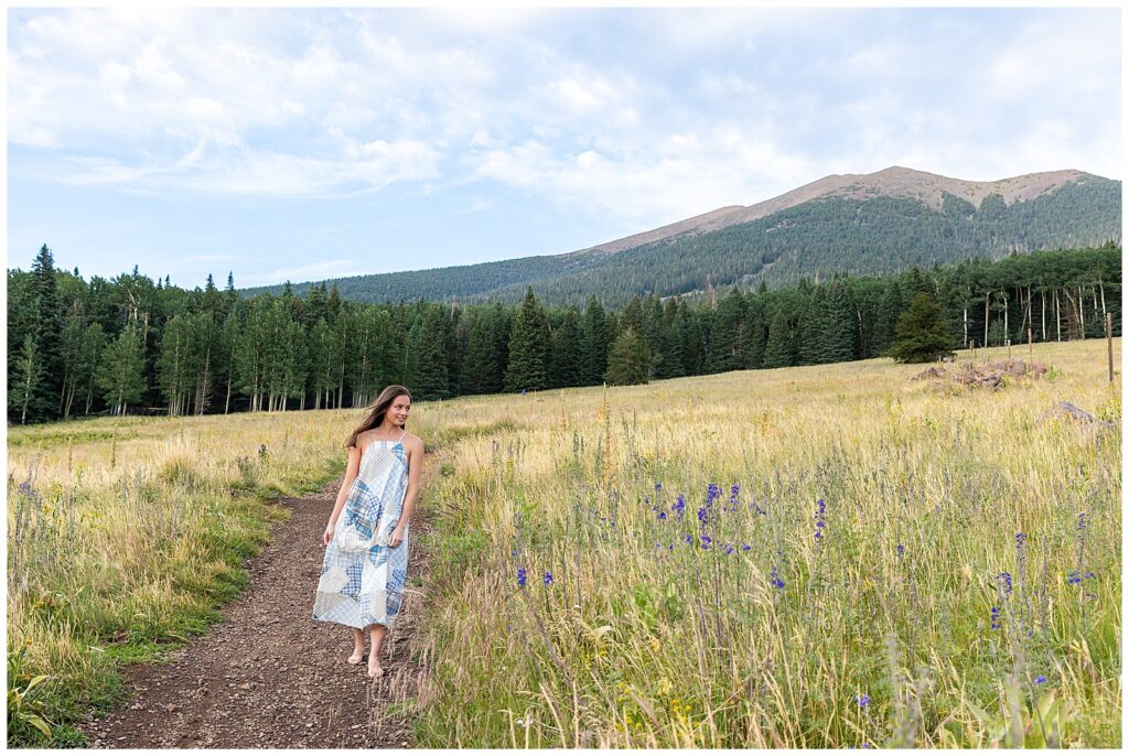 Holly looks toward the mountains as she explores the various trails at the San Francisco Peaks in Flagstaff Arizona during NAU graduation portraits with Bayley Jordan Photography